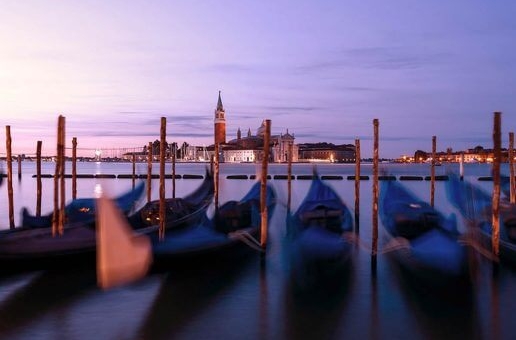 A row of boats sitting in the water at night time
