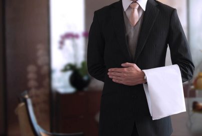 A person in a suit holding a towel over their arm
