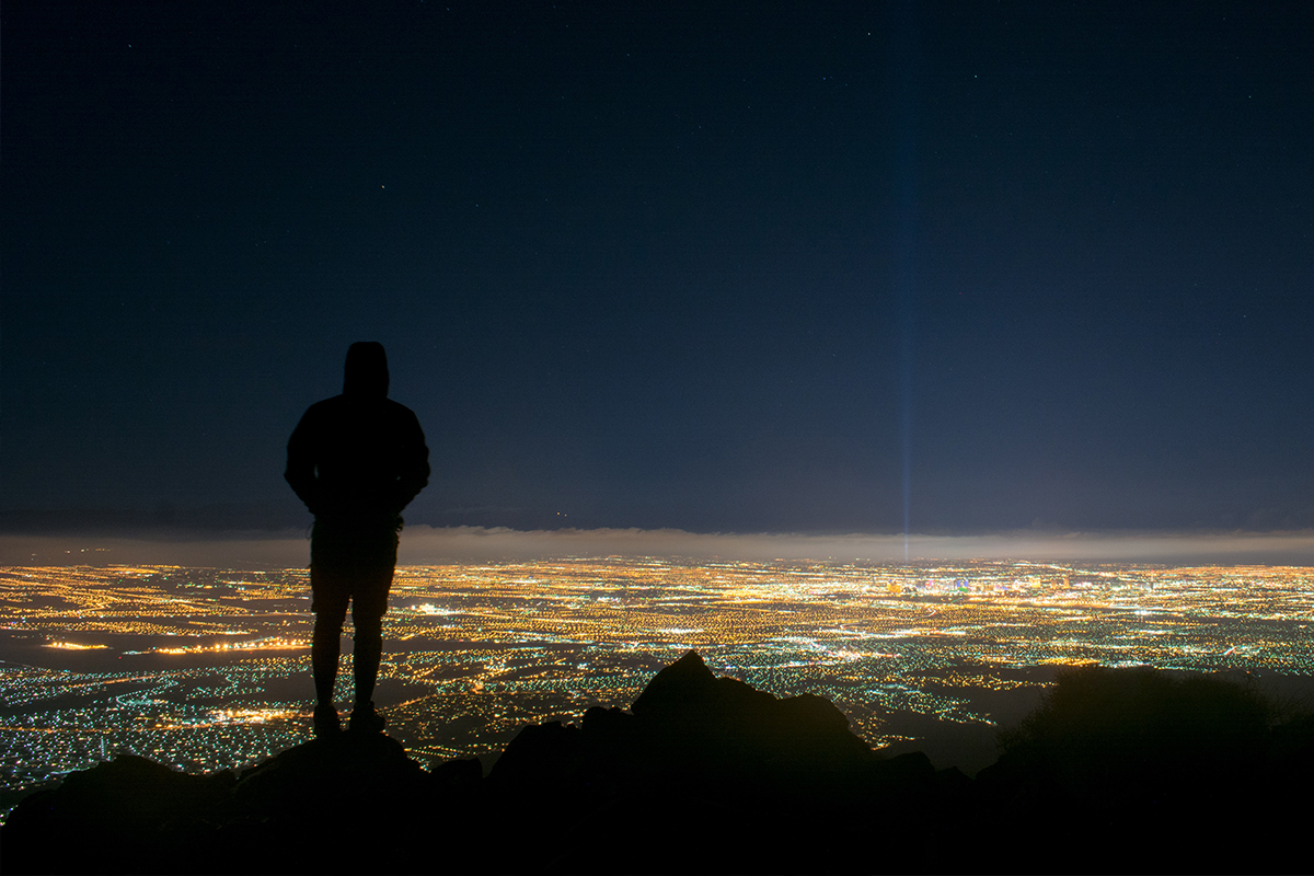 Image of the silhouette of a person overlooking a city at night