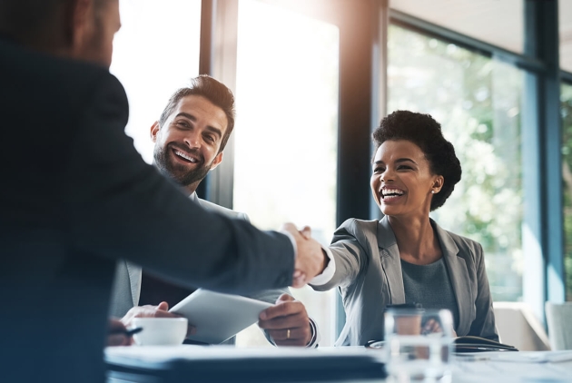 three people shaking hands at a conference table