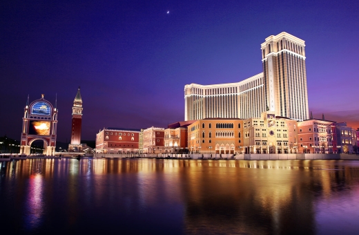 The Venetian Macao at night with a blue sky and the moon over the lagoon.